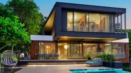 Vista di una bellissima casa di design con piscina con grandi finestre illuminate durante il tramonto