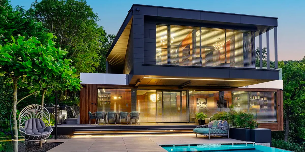 Vista di una bellissima casa di design con piscina con grandi finestre illuminate durante il tramonto
